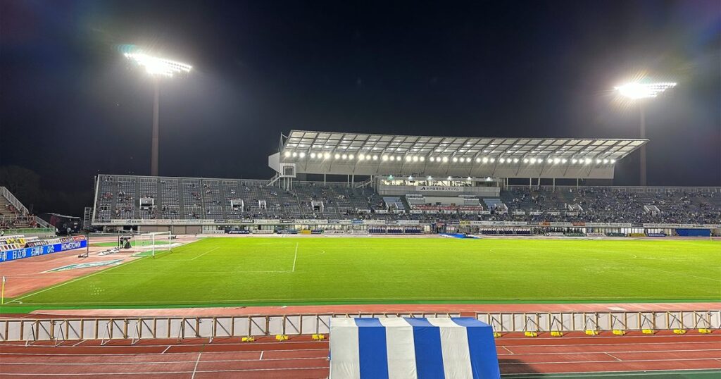 ナイター照明に照らされた水戸信用金庫スタジアムのピッチとメインスタンド