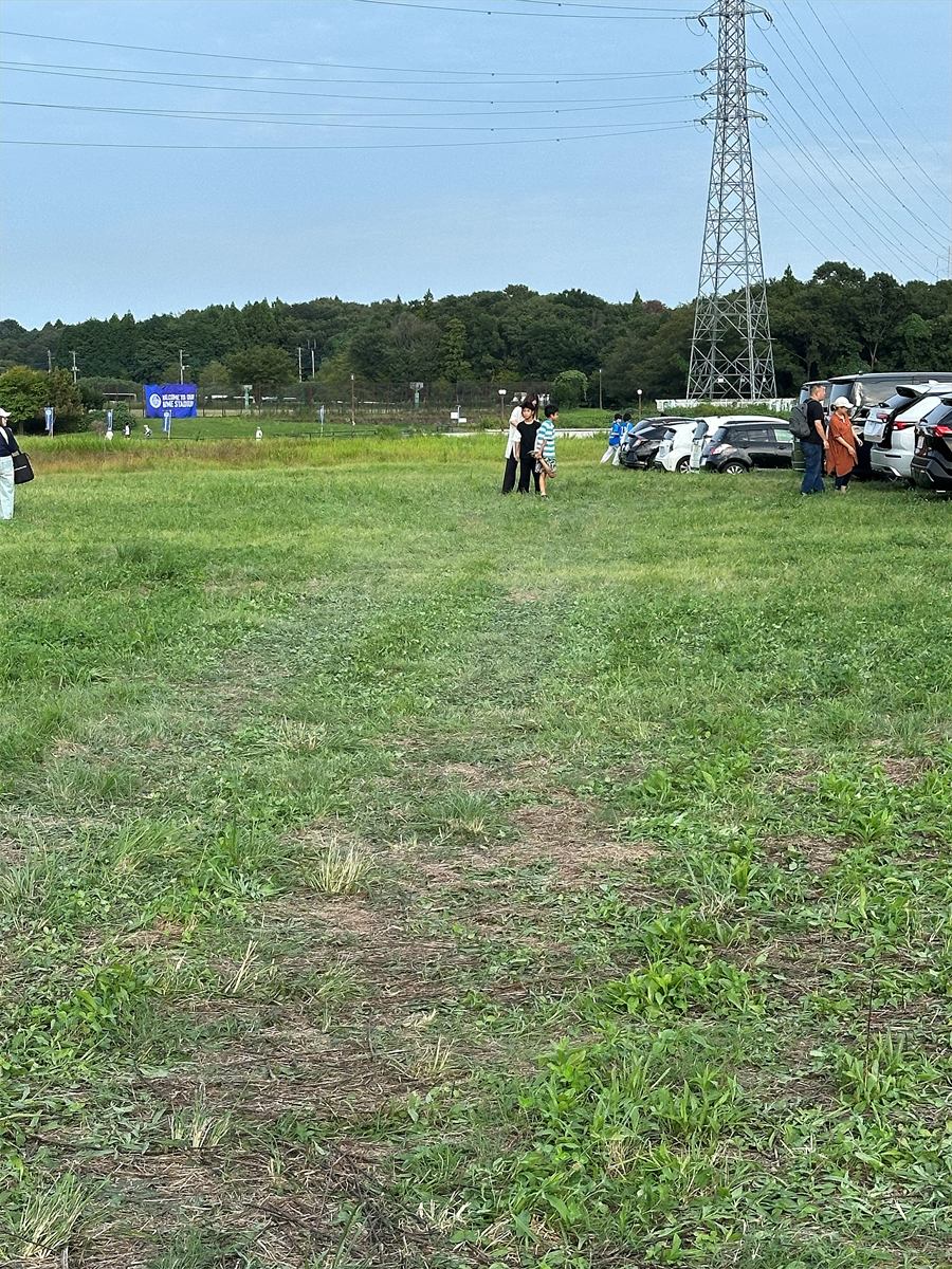 笠松運動公園の草地の駐車場とスタジアムへ向かう道。芝生が伸びている