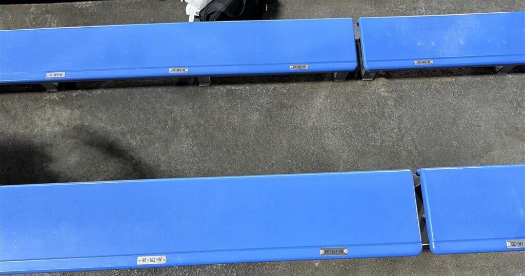 水戸信用金庫スタジアムのバックスタンド自由席。背もたれのない平らな青いベンチが並んでいる